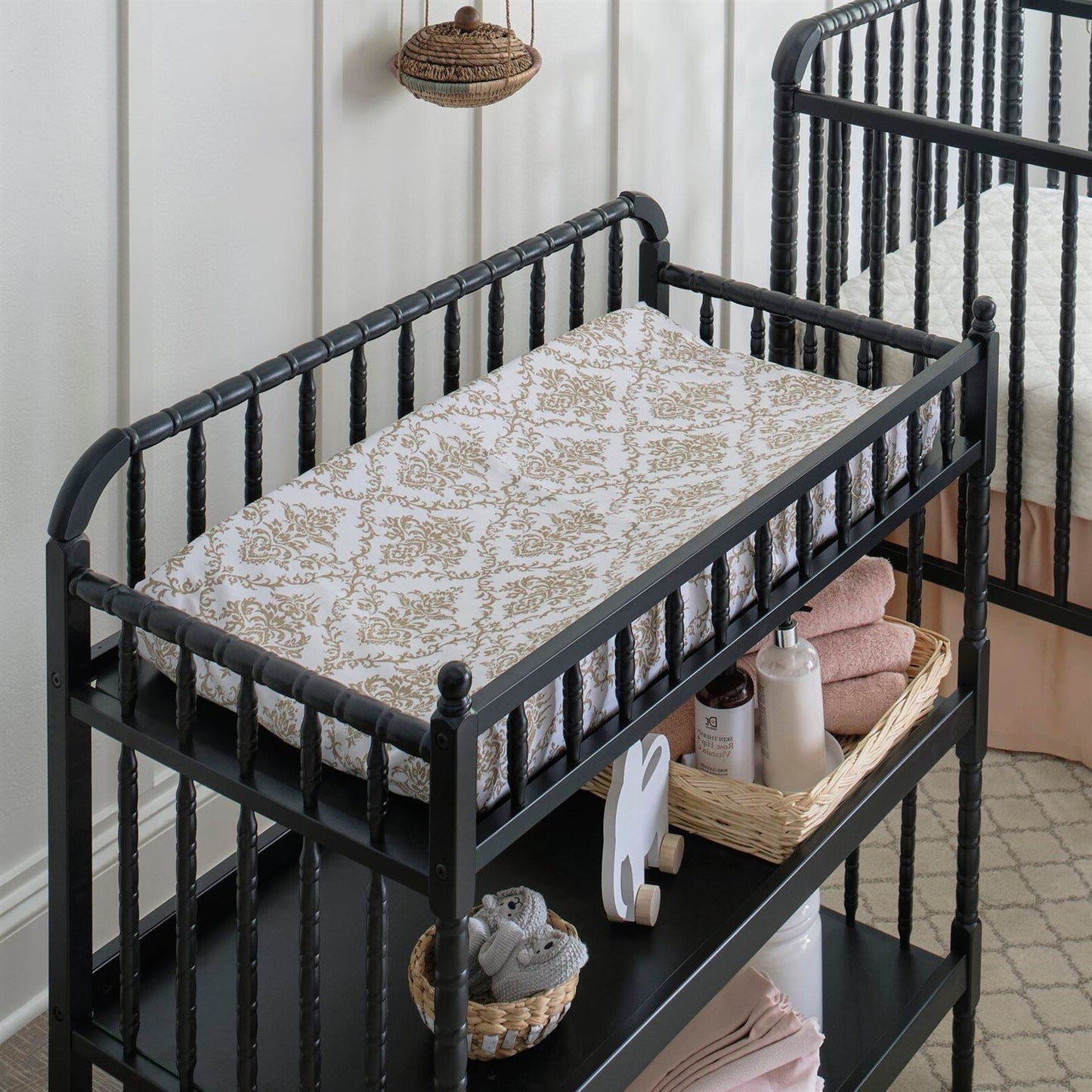 Black crib with patterned mattress and baby care items in a nursery setting
