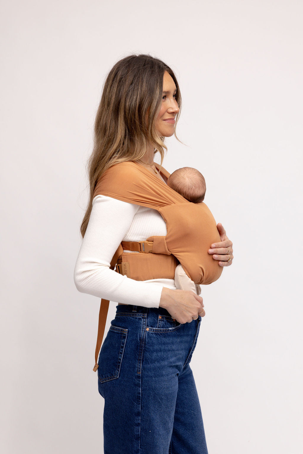 Mom wearing WildBird Willow Aerial Newborn Buckle Wrap front carry facing in