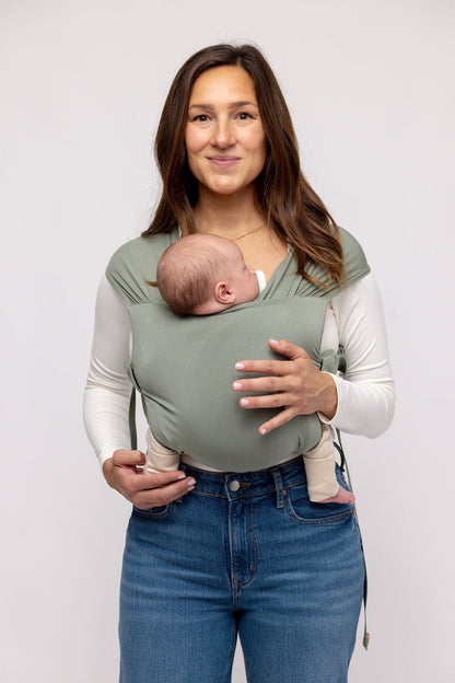 Mom wearing WildBird Aerial Newborn Buckle Wrap with newborn front carry facing in