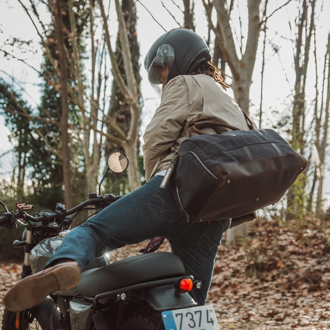 Person on a motorcycle with a bag in a forest setting