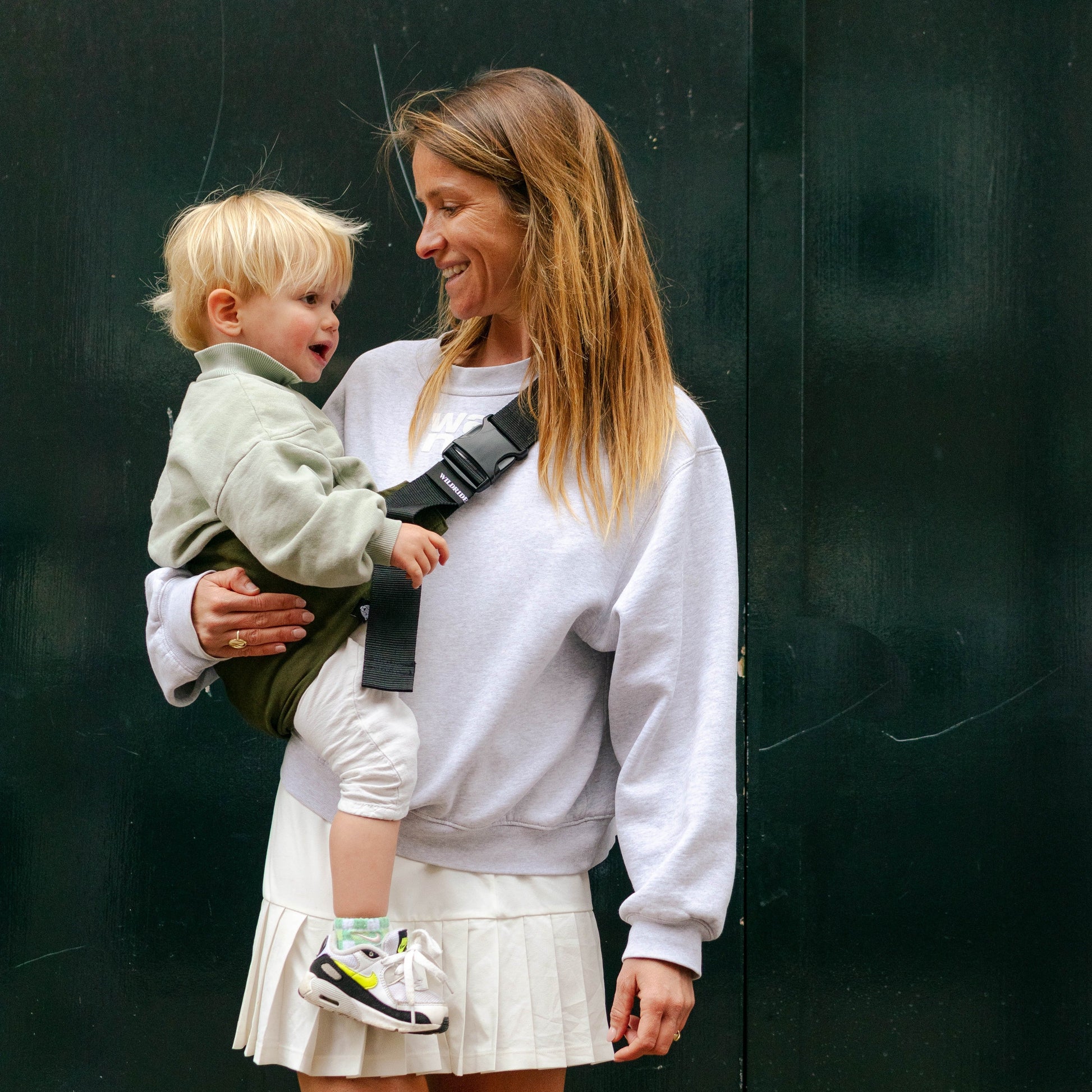 Mom holding todder in WildRide Army green carrier