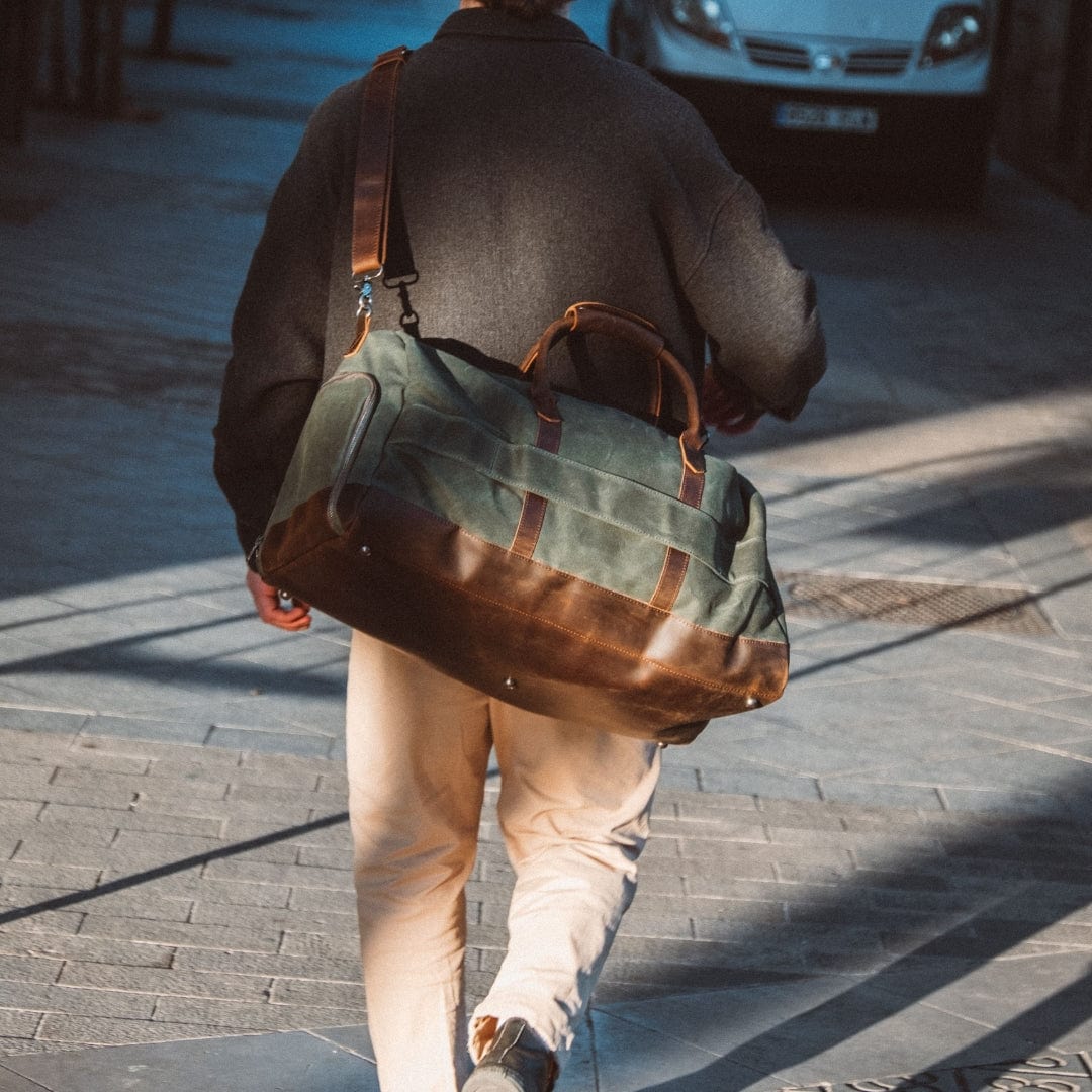 Dad walking on a sidewalk with a large green and brown duffel bag.