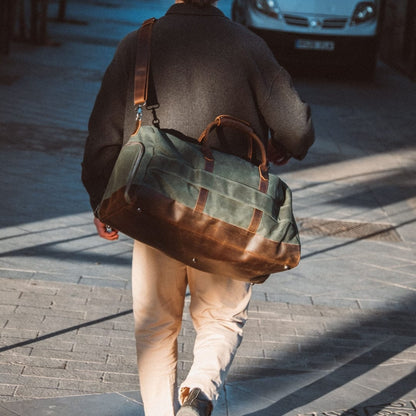 Dad walking on a sidewalk with a large green and brown duffel bag.