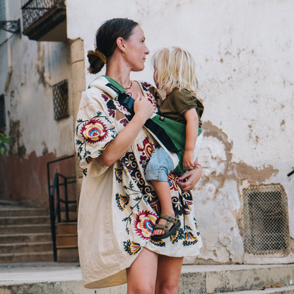 Mom holding toddler with a Wildride USA foldable toddler hip carrier in bold green graphic pattern